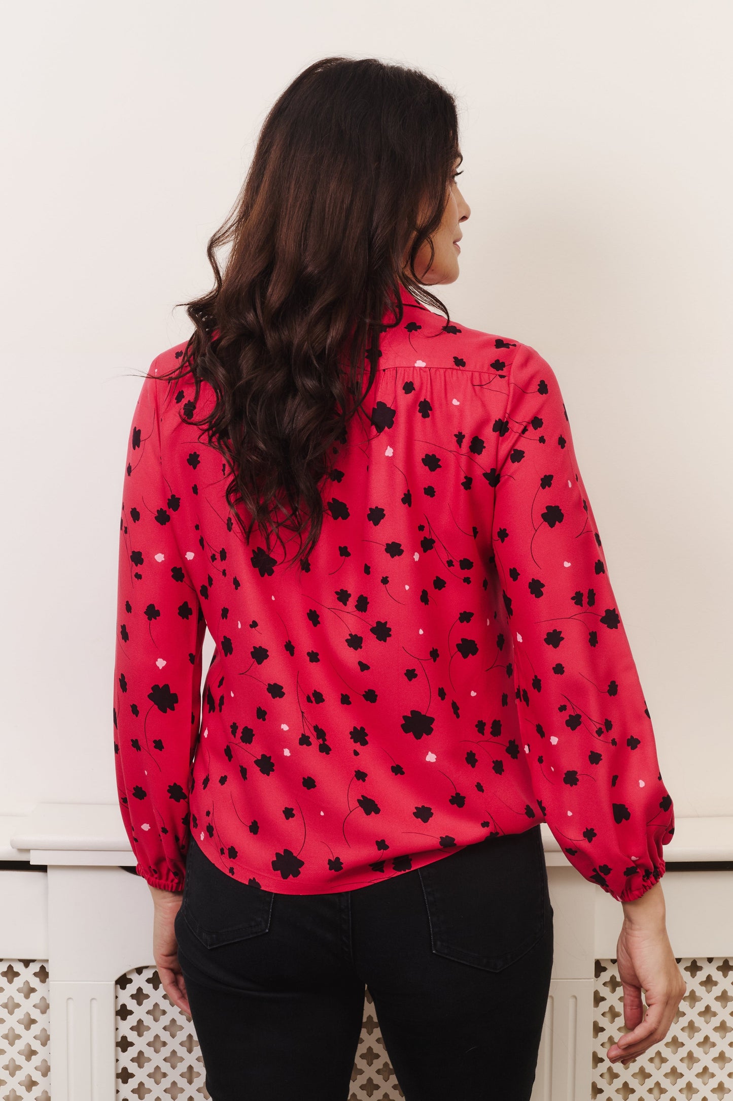 Model with fuller bust wears vibrant crimson coloured blouse, with hidden button, rounded collar and elasticated cuffs. Fabric is 100% LENZING™ ECOVERO™ Viscose - which has a lightly crisp touch with a soft fluid drape. Its fully opaque and has a soft semi-matte sheen.