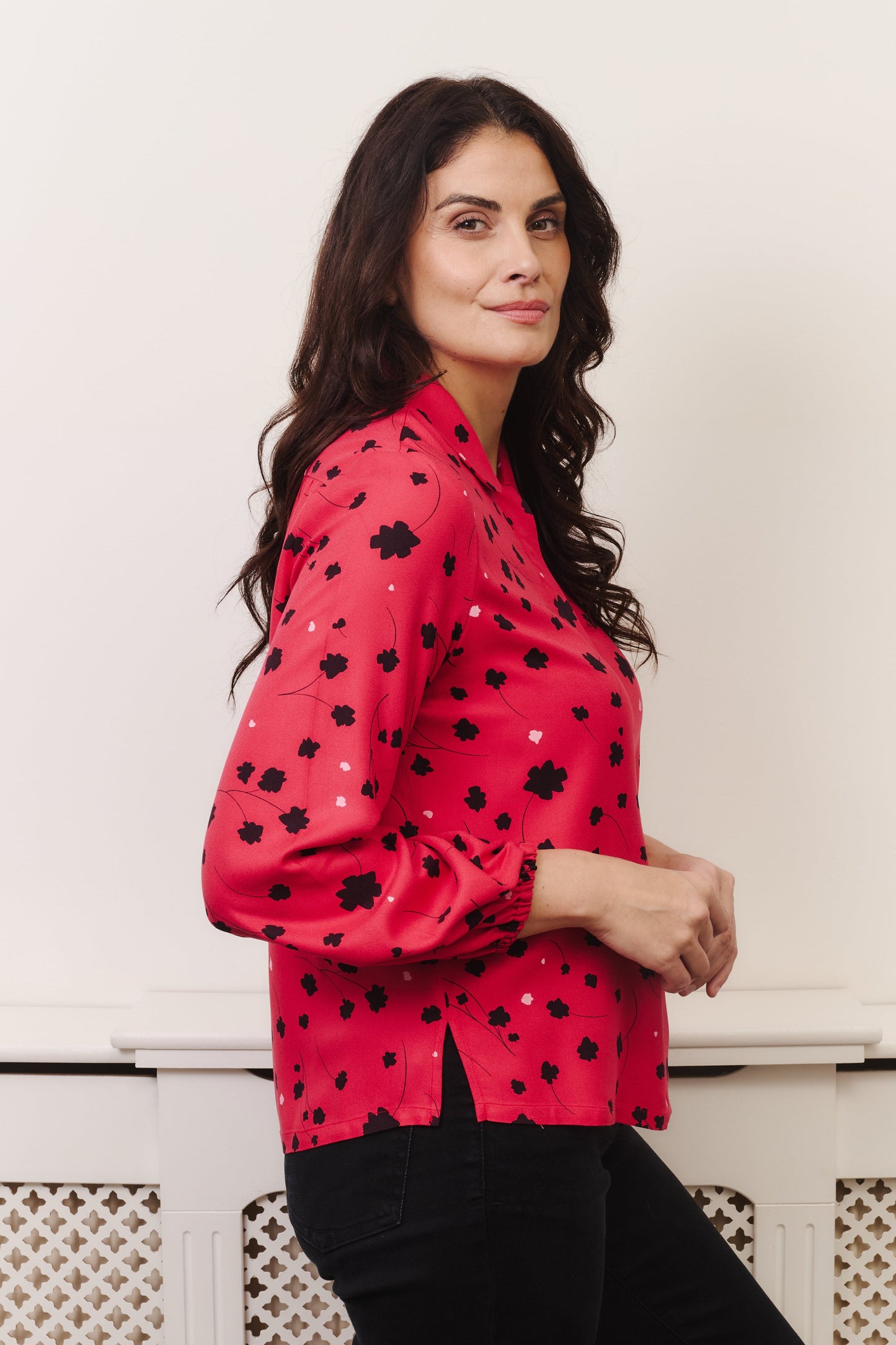 Model with fuller bust wears vibrant crimson coloured blouse, with hidden button, rounded collar and elasticated cuffs. Fabric is 100% LENZING™ ECOVERO™ Viscose - which has a lightly crisp touch with a soft fluid drape. Its fully opaque and has a soft semi-matte sheen.