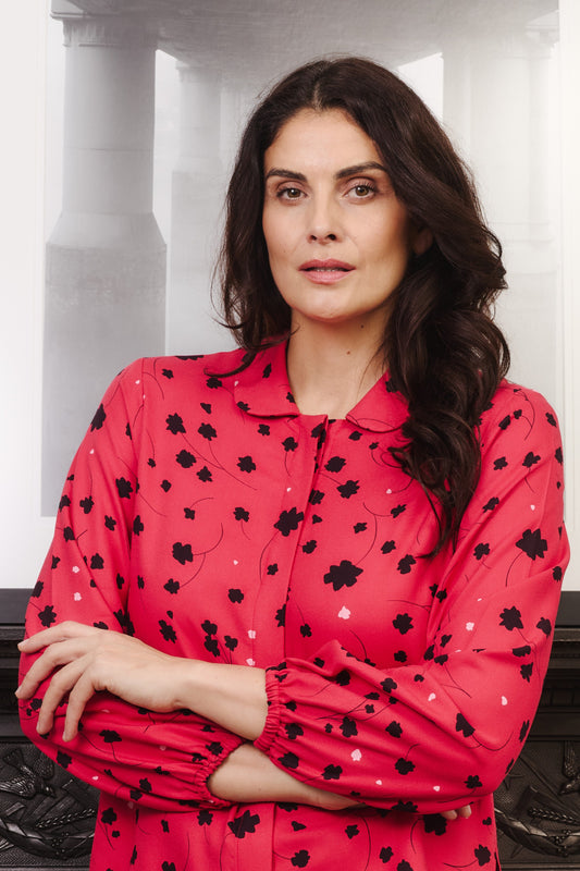 Model with fuller bust wears vibrant crimson coloured blouse, with hidden button, rounded collar and elasticated cuffs. Fabric is 100% LENZING™ ECOVERO™ Viscose - which has a lightly crisp touch with a soft fluid drape. Its fully opaque and has a soft semi-matte sheen.