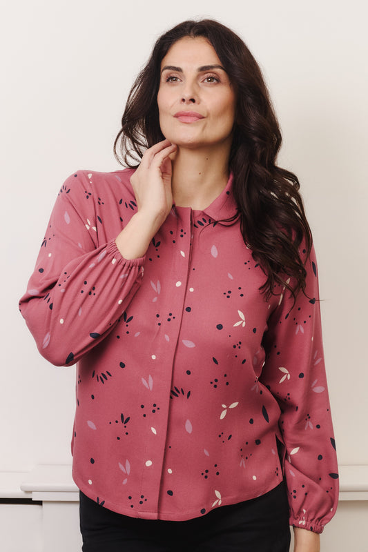 Model with fuller bust wears rose coloured blouse, with hidden button, rounded collar and elasticated cuffs. Fabric is 100% LENZING™ ECOVERO™ Viscose - which has a lightly crisp touch with a soft fluid drape. Its fully opaque and has a soft semi-matte sheen.