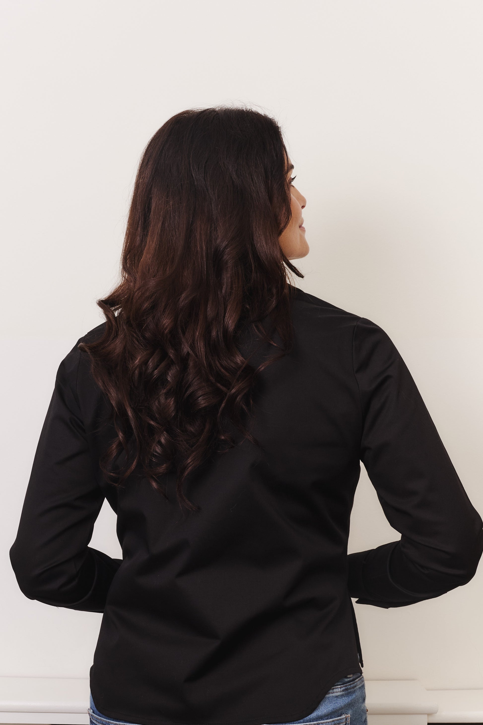 Fuller bust model wearing black organic cotton shirt. Back of shirt is shown. By Kin+Star