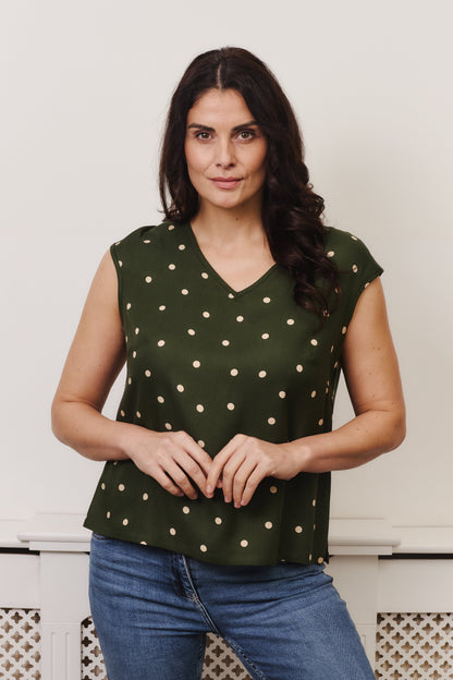 Fuller bust Woman wearing green polka dot v-neck, cap sleeve top, gentle loose fitting in style. Fabric is 100% LENZING™ ECOVERO™ Viscose. The
ECOVERO™ Viscose crepe is a classic crepe with a lightly crisp touch and a soft fluid drape.