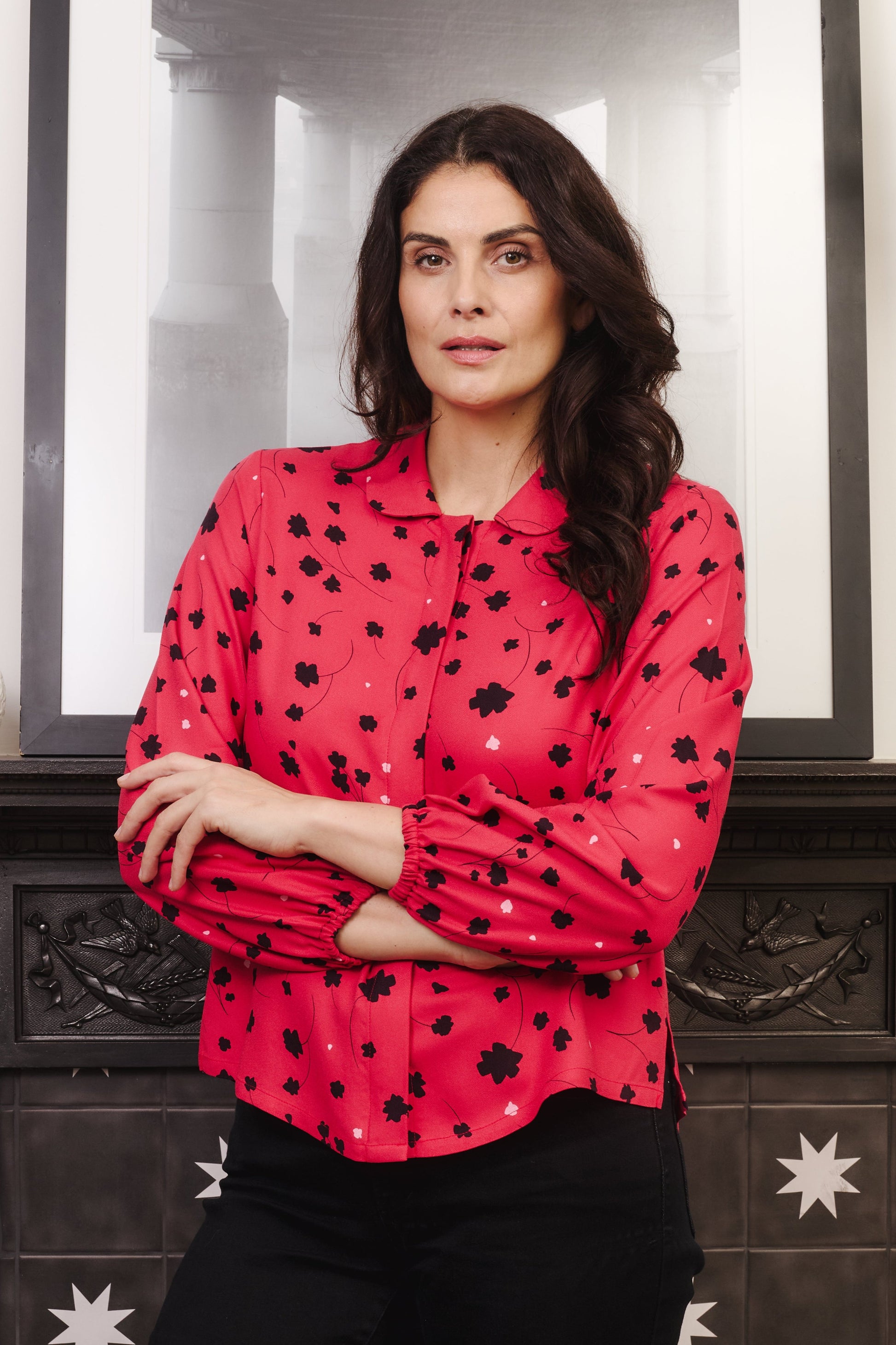 Model with fuller bust wears vibrant crimson coloured blouse, with hidden button, rounded collar and elasticated cuffs. Fabric is 100% LENZING™ ECOVERO™ Viscose - which has a lightly crisp touch with a soft fluid drape. Its fully opaque and has a soft semi-matte sheen.