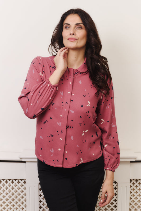 Model with fuller bust wears rose coloured blouse, with hidden button, rounded collar and elasticated cuffs. Fabric is 100% LENZING™ ECOVERO™ Viscose - which has a lightly crisp touch with a soft fluid drape. Its fully opaque and has a soft semi-matte sheen.